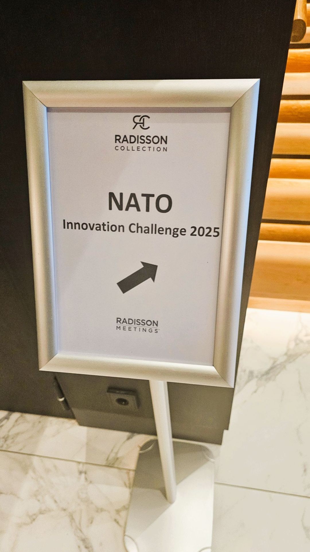 Sign for NATO Innovation Challenge 2025 at Radisson Collection, with an arrow pointing direction.